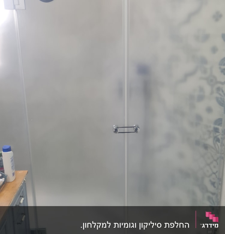 מקלחון זכוכית עם ראש מקלחת ומגבת תלויה